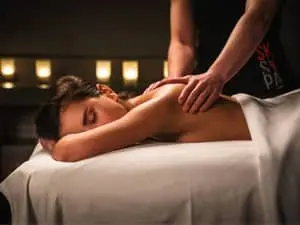 Handen geven comfort aan de schouderbladen van de patiënt