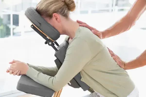 Séance de massage sur chaise pour une femme sur son lieu de travail